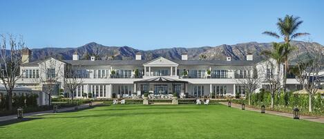 A large, multi-story building with a symmetrical facade, a central entrance with a portico, and a well-maintained lawn in front.