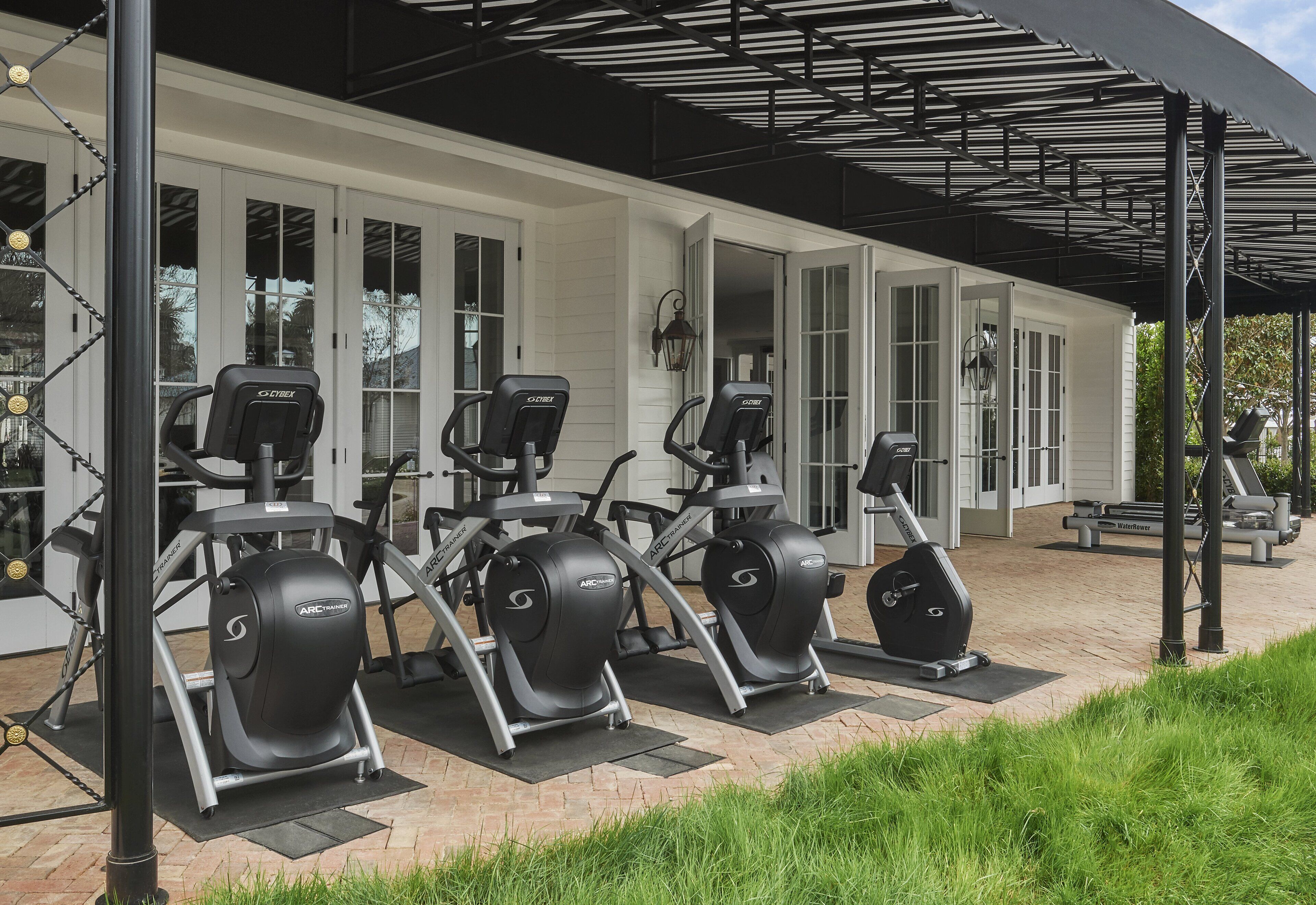 Un espace de remise en forme extérieur abrité, équipé de vélos d’appartement et d’autres appareils d’exercice.