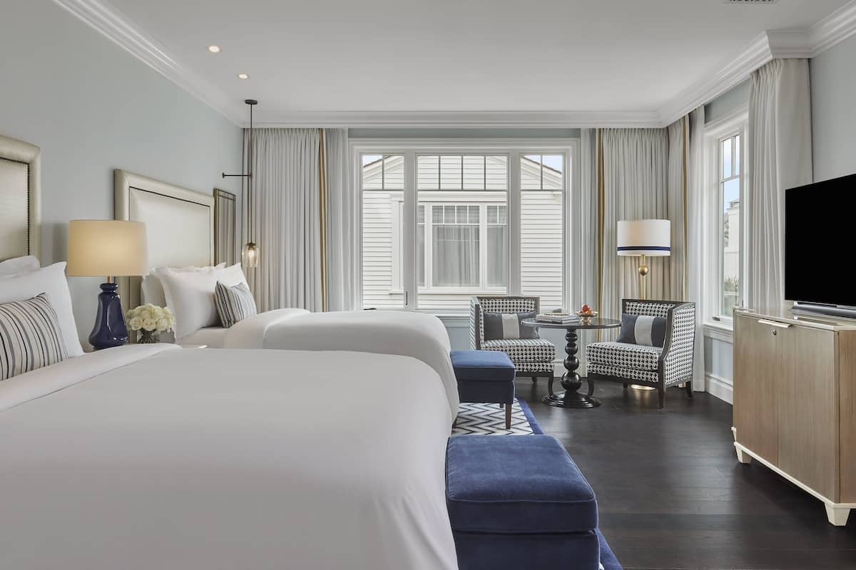 Een hotelkamer met een groot bed, twee stoelen, een tafeltje en een televisie.