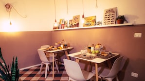 A dining area with two tables, white chairs, and a potted plant. - Arsenale Suites (Verona)