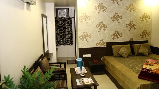 A bedroom with a bed, bedside table, and a wall-mounted air conditioner. - Hotel Abhinandan Inn Jaipur (Jaipur)