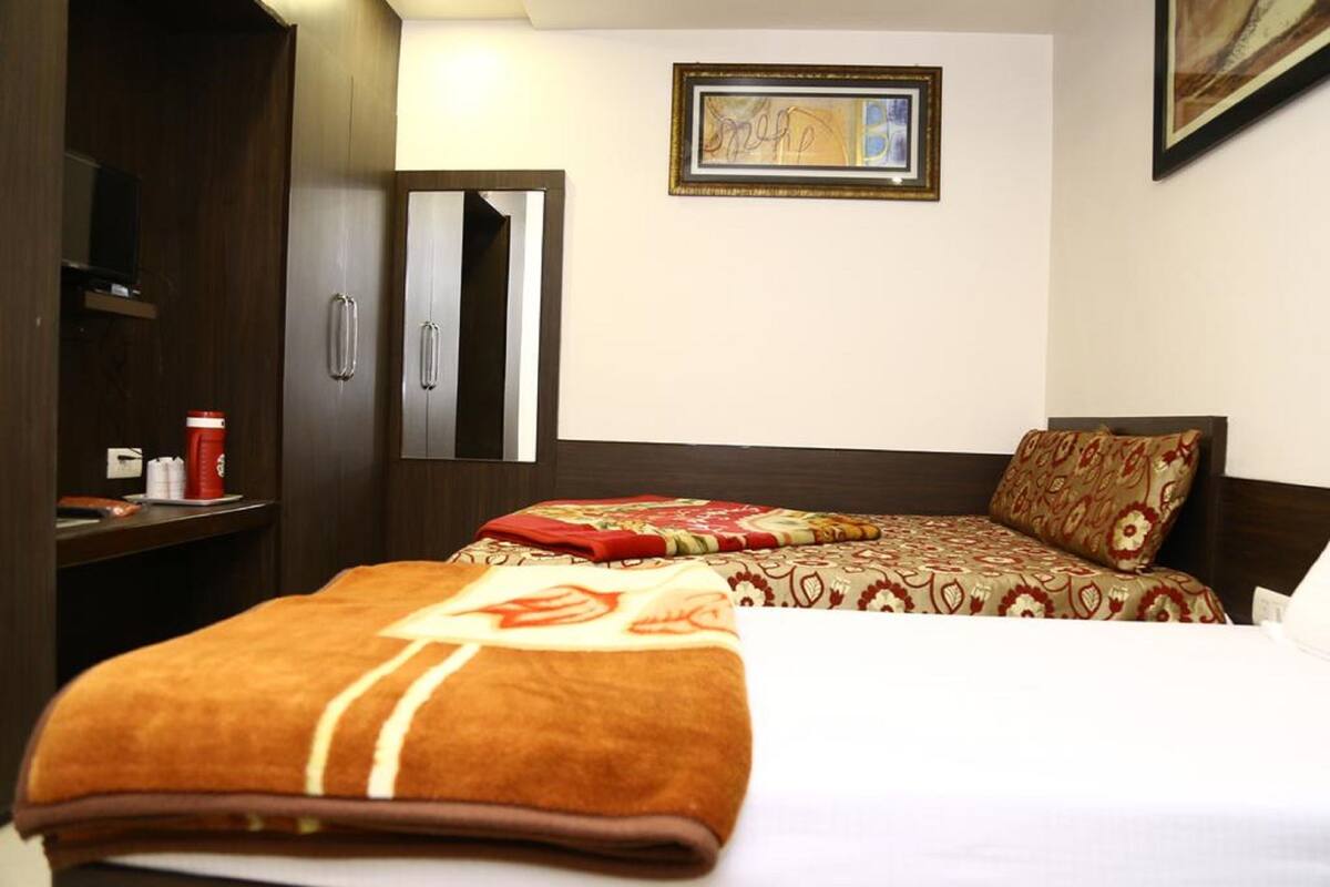 Une chambre d’hôtel avec un lit, une table de chevet, un miroir et un tableau encadré au mur.