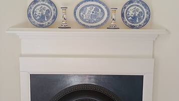 A fireplace with three blue and white decorative plates and two matching vases on the mantel.