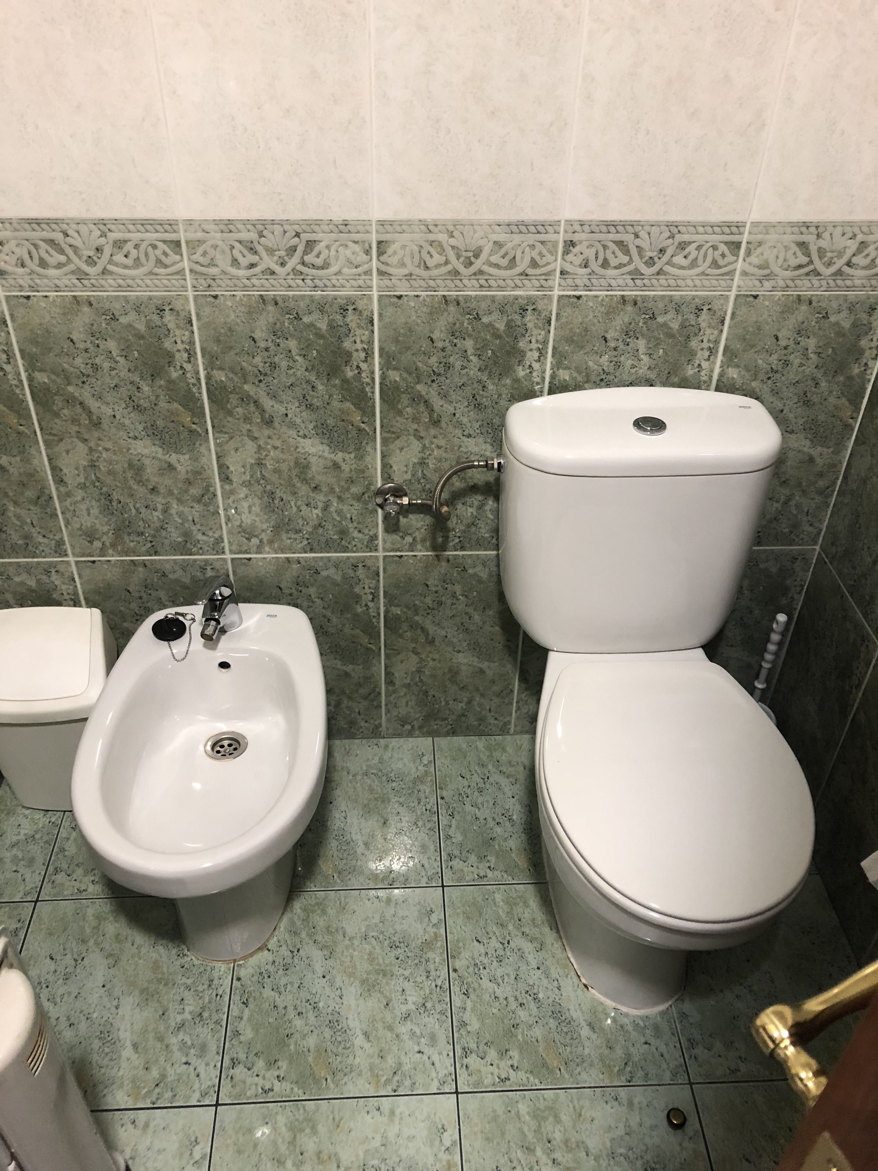 A bathroom with a bidet, toilet, and sink.