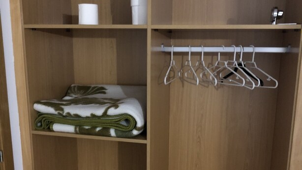 Un armario de madera con estantes y barra para colgar.