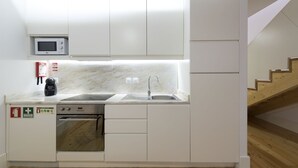 Een kleine keuken met een inbouwmagnetron, oven en spoelbak.