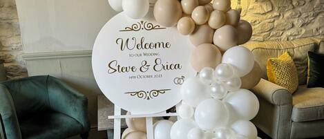 Un'elegante composizione di palloncini con un cartello che riporta: "Benvenuti al nostro matrimonio Steve & Erica 14 ottobre 2023".