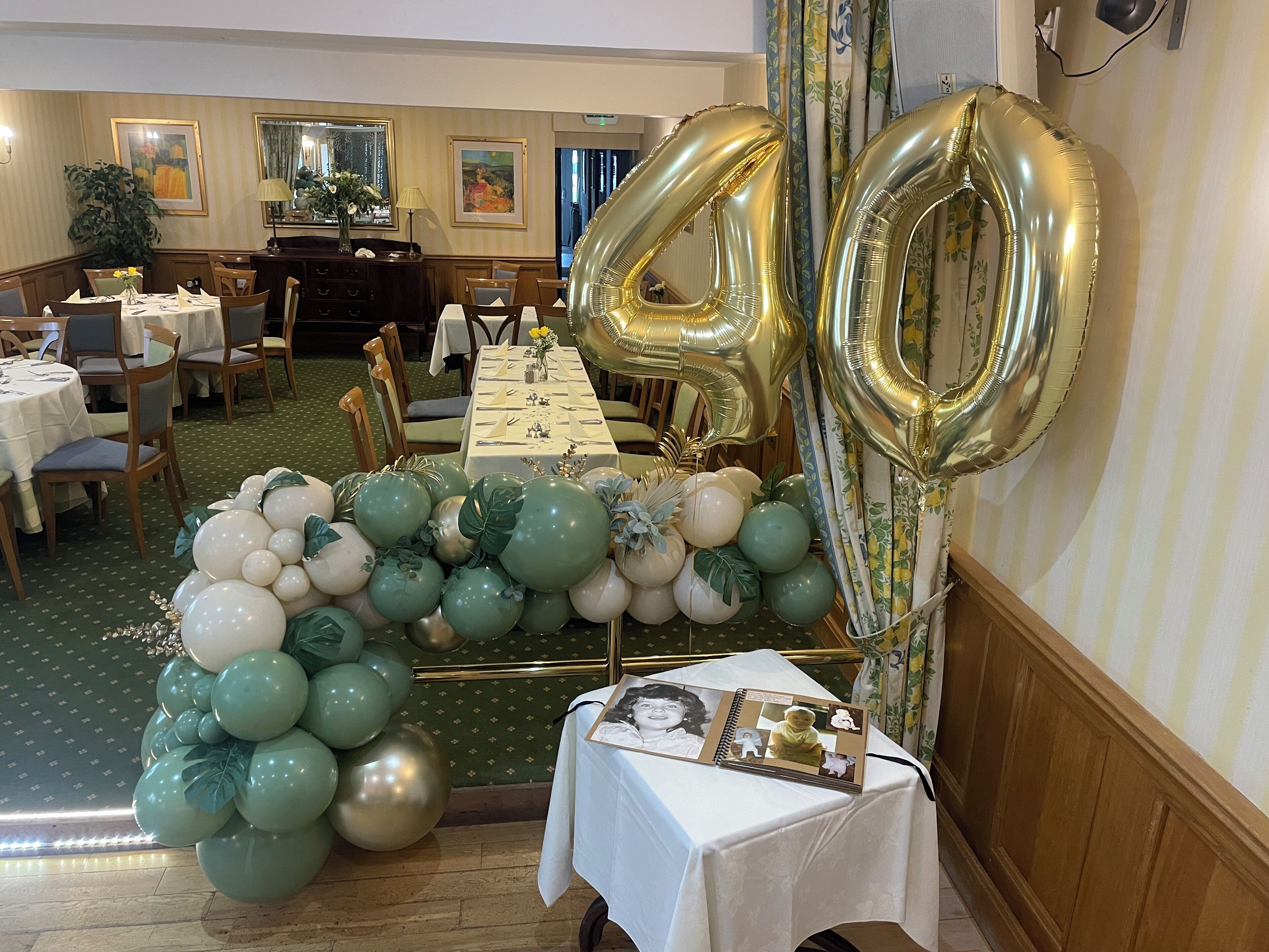 A dining area with round tables, a buffet setup, and a wall-mounted photo album.