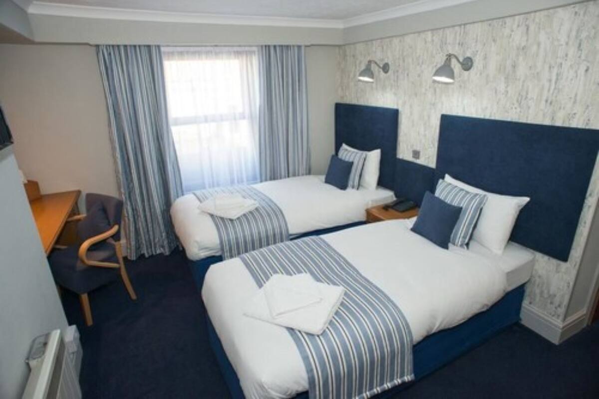 A hotel room with two beds, a desk, and a chair.