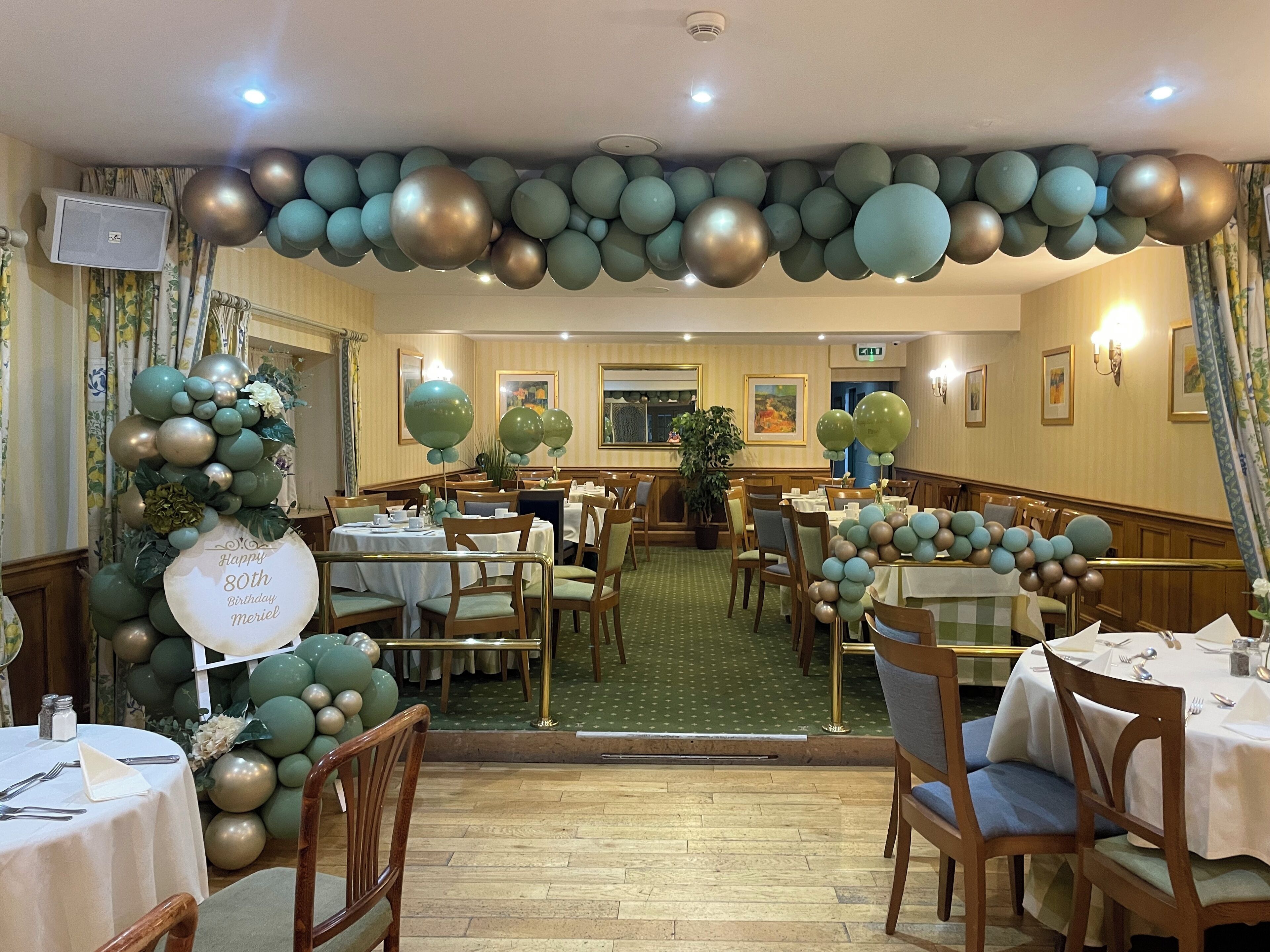 Comedor de hotel con mesas redondas, sillas y un techo decorado con globos.