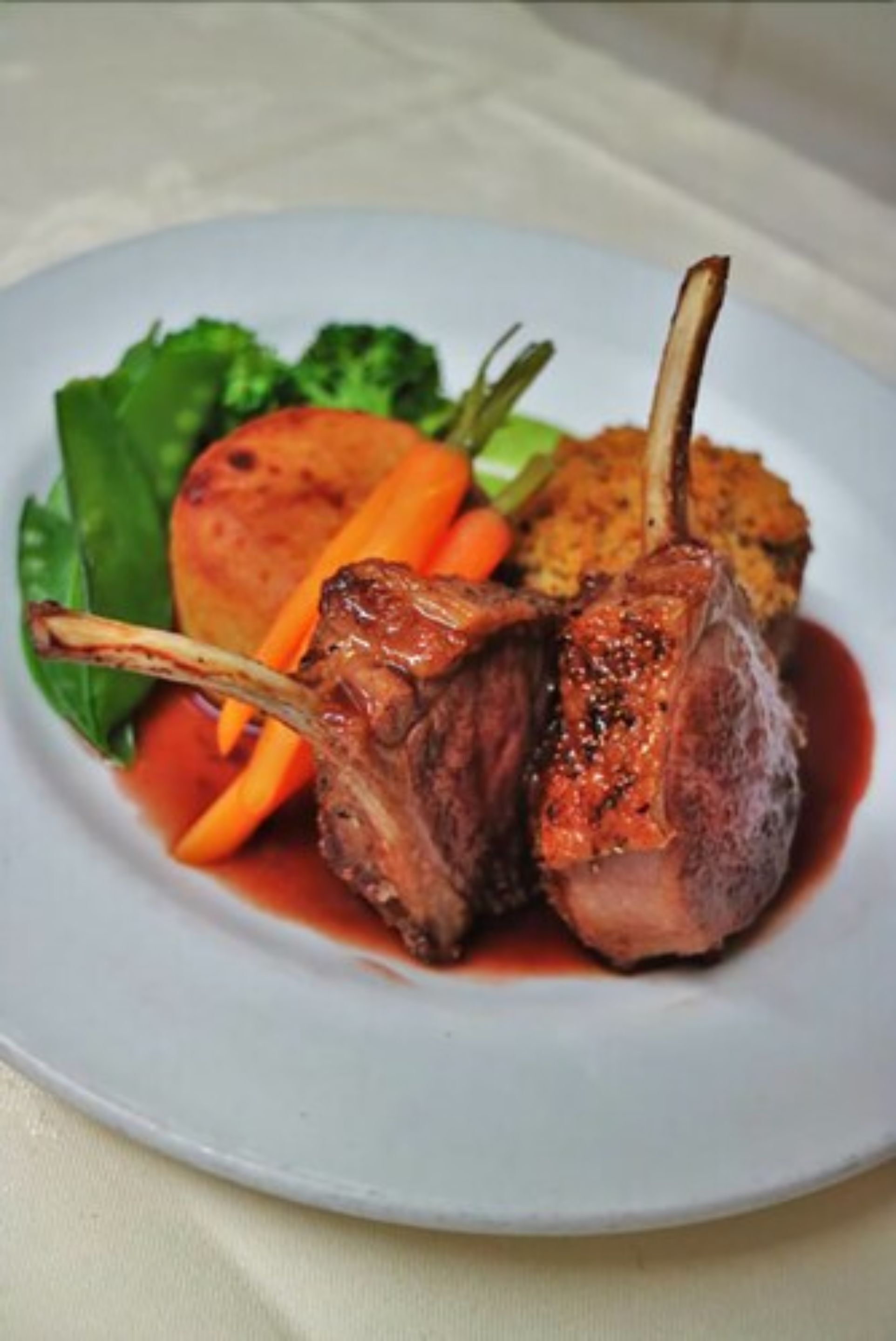 A plate with a lamb chop, roasted potatoes, and carrots.
