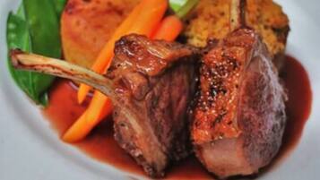 A plate with a lamb chop, roasted potatoes, and carrots.