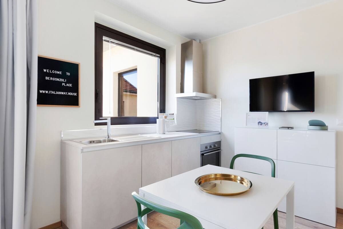 A compact kitchen with a built-in oven, a sink, and a dining area with a table and chairs.