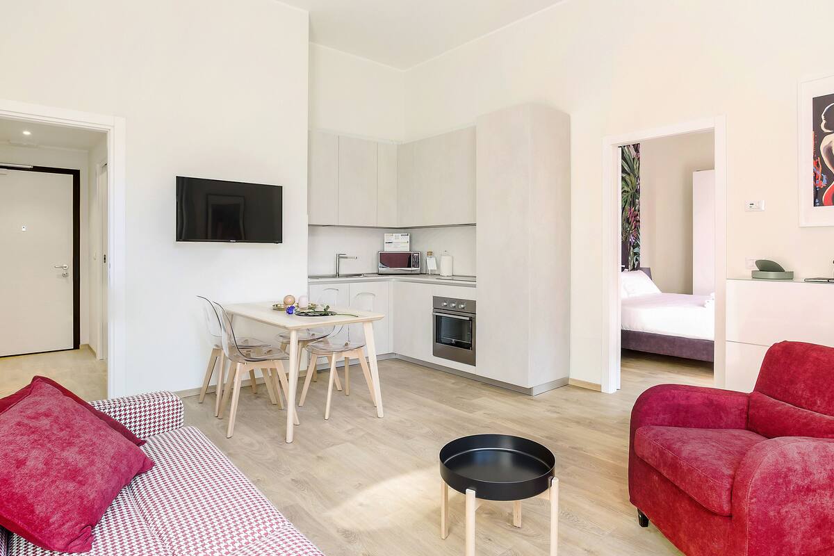 A compact living space with a kitchenette, a dining area, and a bedroom.