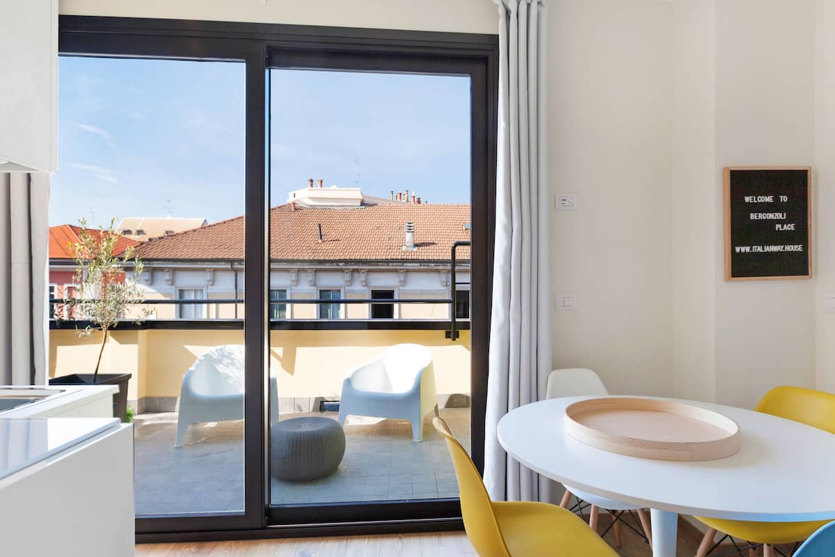 A modern room with a sliding glass door leading to a balcony, a small round table with a tray, and a chair.