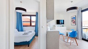 A modern hotel room with a bed, a desk, and a chair. There is a TV on the wall and a window with curtains. - Italianway   - Bergonzoli (Milan)