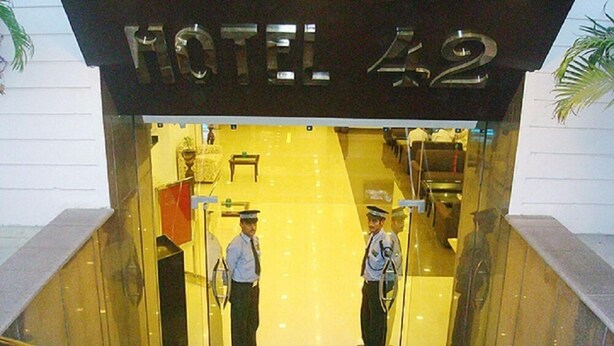 A hotel entrance with two uniformed staff members standing at the reception. - Hotel 42 (Amritsar)