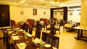 A dining area with tables set for meals, chairs, and a sofa. - Hotel 42 (Amritsar)