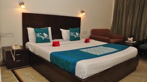 A neatly made bed with white and teal bedding, a dark headboard, and two bedside lamps. - Hotel 42 (Amritsar)
