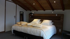 Une chambre à coucher avec une tête de lit en bois, un lit recouvert de linge de lit blanc et deux lampes de chevet.