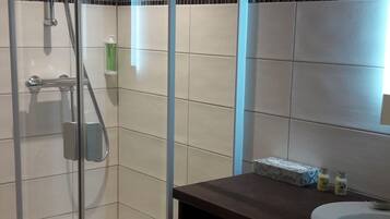 A modern bathroom with a glass-enclosed shower, a dark wooden vanity, and a white sink.