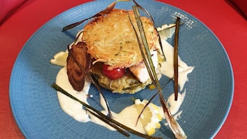 A plate with a sandwich, some vegetables, and a creamy sauce on a blue plate.