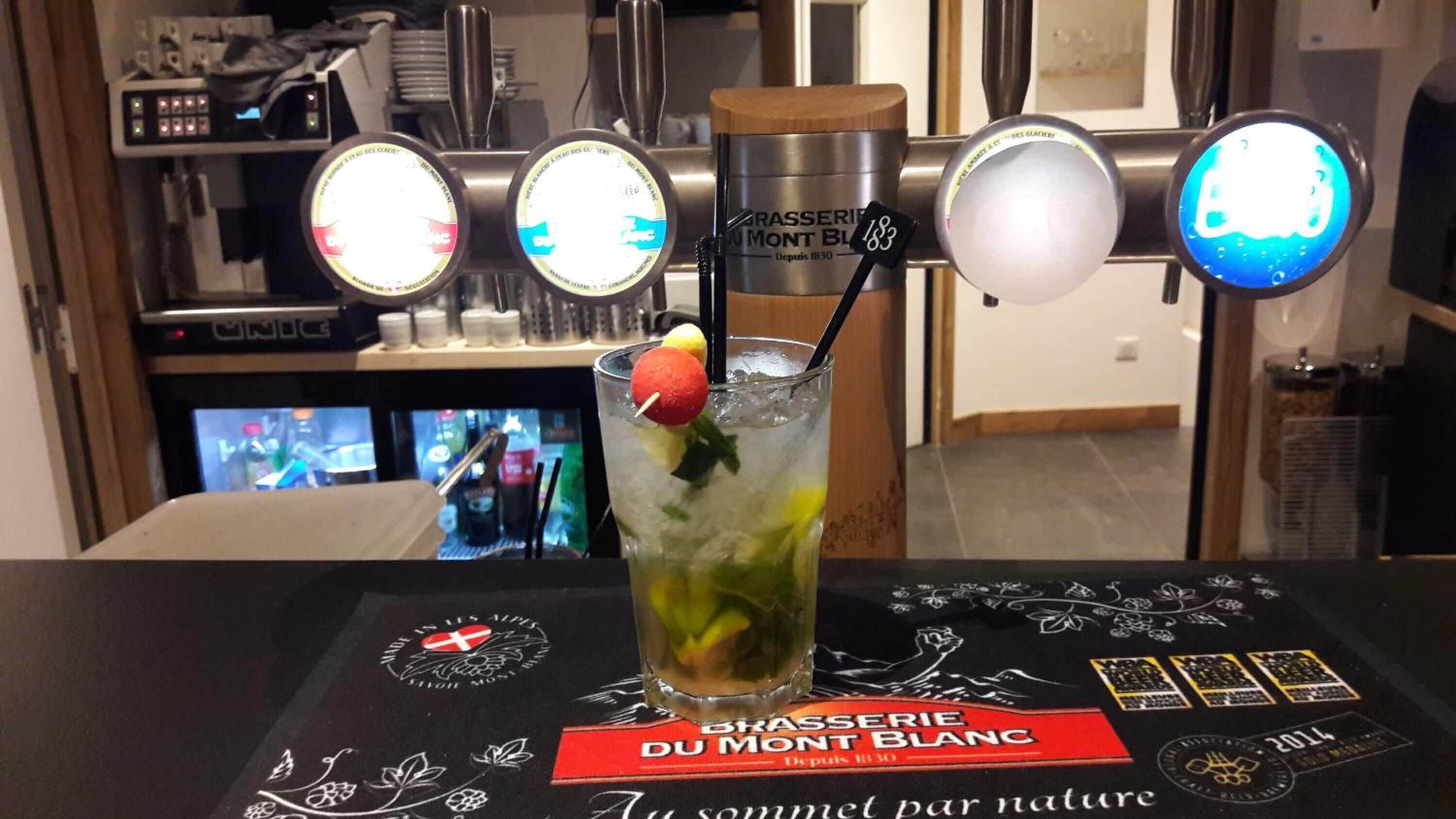 A bar area with a drink, a menu, and a TV screen in the background.