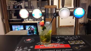 A bar area with a drink, a menu, and a TV screen in the background.
