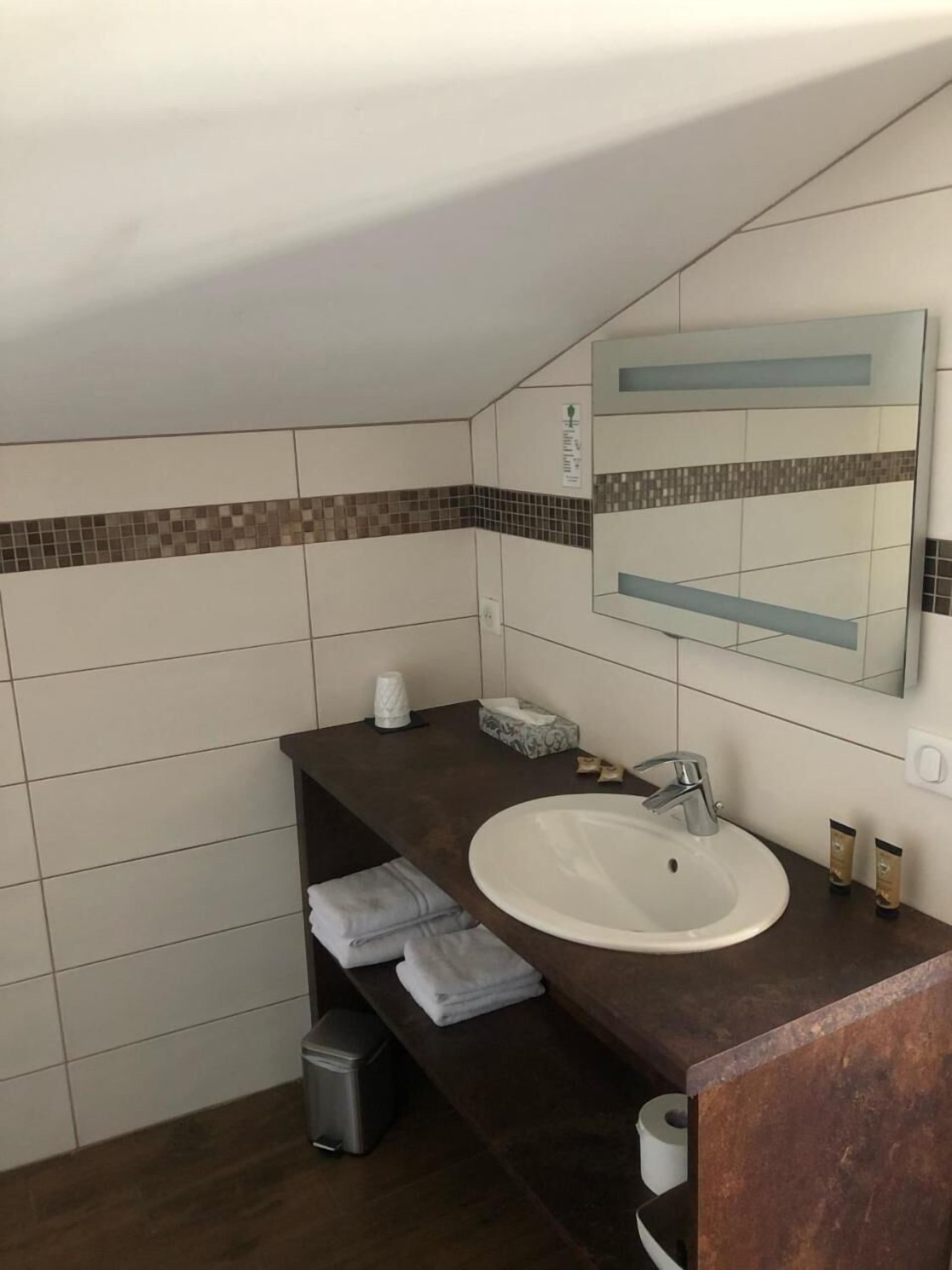 Un bagno con un lavandino bianco, un piano di lavoro scuro e pareti rivestite di piastrelle.