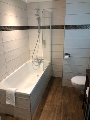 A bathroom with a bathtub, a shower, and a toilet. - L'Alpin (Landry)