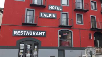 Un edificio rojo con balcones y letreros de hotel y restaurante.