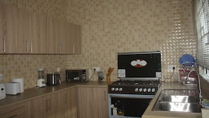 Una cocina con gabinetes de madera, estufa, microondas y pileta.
