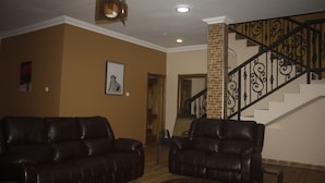 Una sala de estar con dos sofás de cuero, una mesa de centro y una escalera con barandilla de hierro forjado.