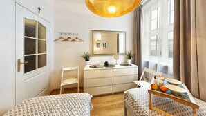 Een kleine slaapkamer met een bed, nachtkastje en een raam met gordijnen.