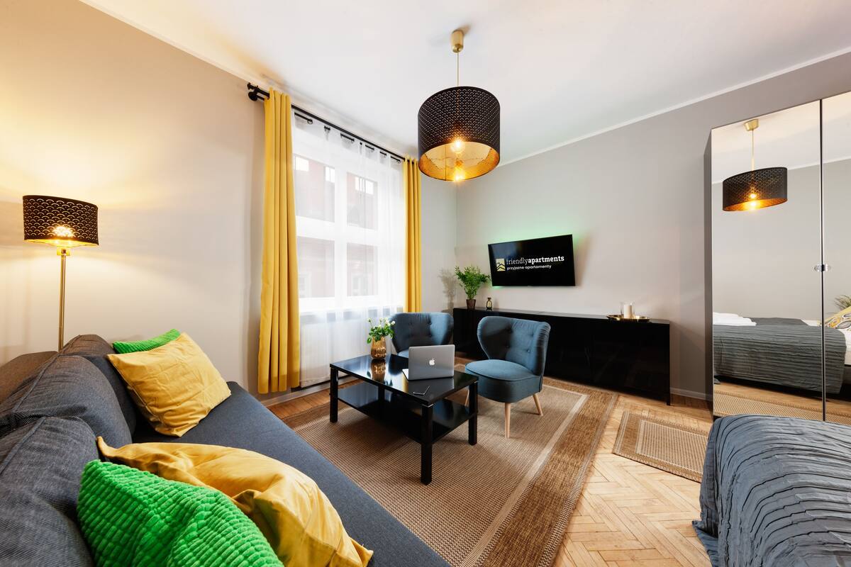 A modern living room with a sofa, armchairs, a coffee table, and a TV mounted on the wall.
