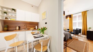 Een moderne keuken met witte kasten, een houten aanrecht en een eethoek met witte stoelen en een tafel.