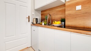Een moderne keuken met witte kasten, een houten aanrechtblad, een roestvrijstalen spoelbak en een fruitschaal.