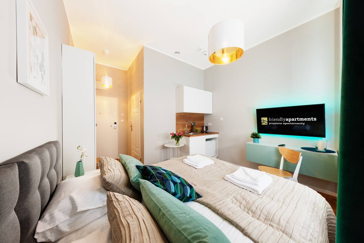 A modern bedroom with a bed, bedside table, and a TV on the wall.
