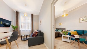 Een moderne woonkamer met een bank, een eettafel en een aan de muur bevestigde televisie.