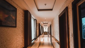 A long, well-lit hallway with patterned walls, large windows, and doors leading to rooms. - Konark Grand Hotel (Mirzapur)