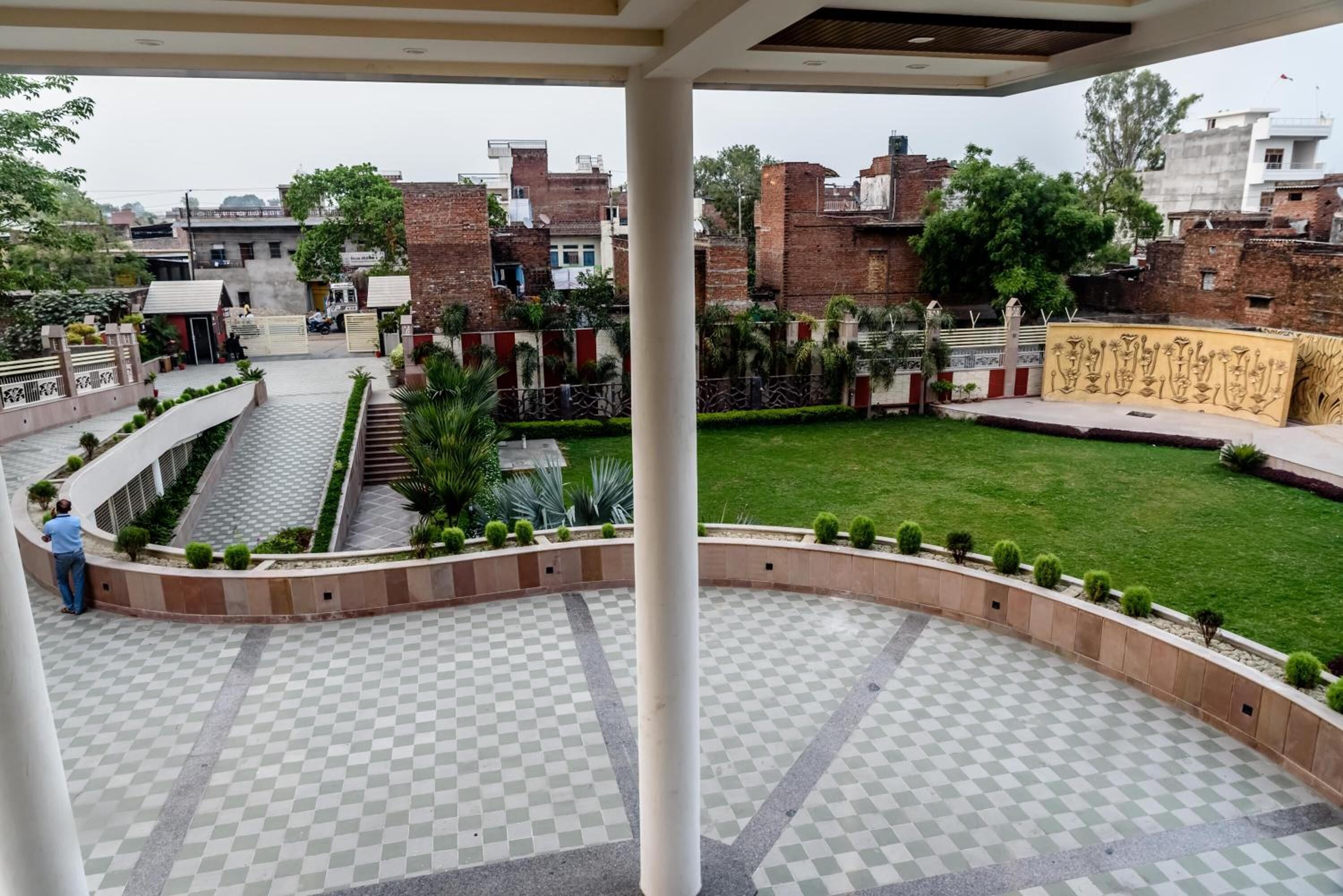 A courtyard with a checkered floor, a central column, and a grassy area.