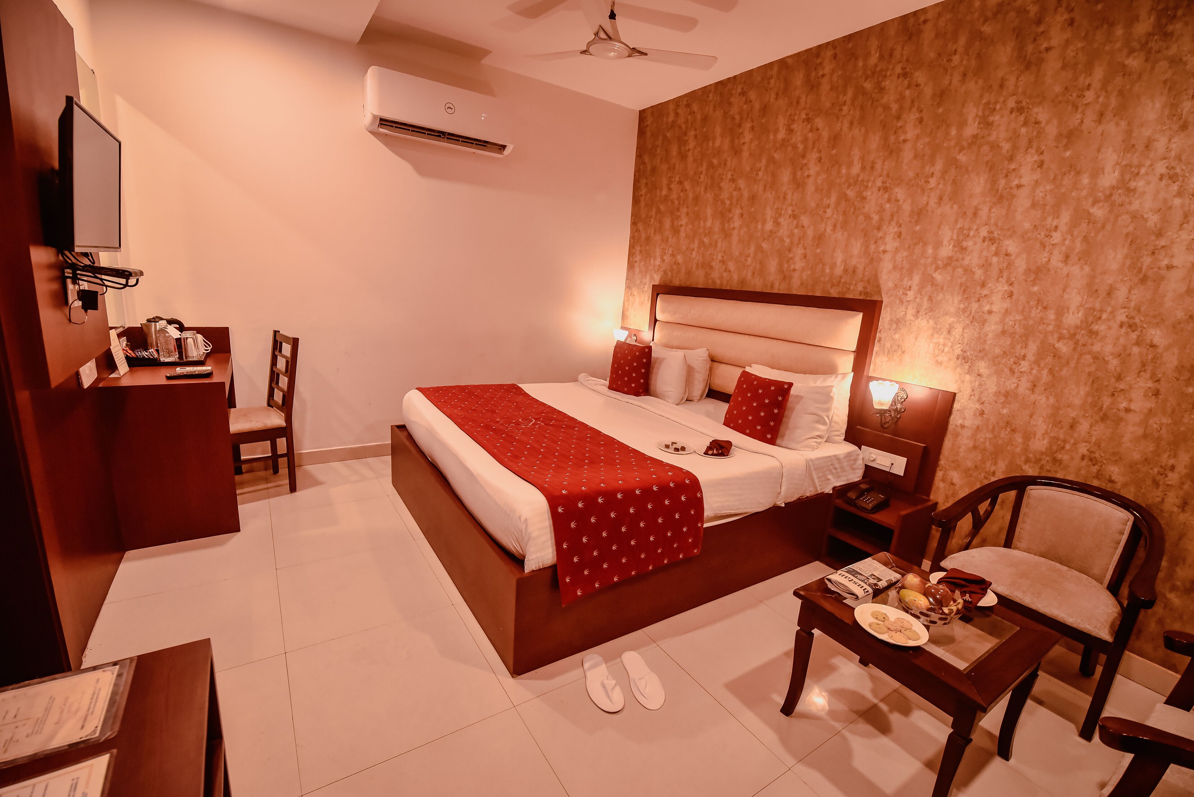 A hotel room with a bed, bedside table, chair, and a desk with a chair.