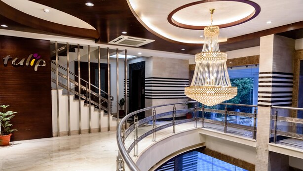 A modern hotel interior with a grand staircase, a chandelier, and a sign that reads "tulip". - Konark Grand Hotel (Mirzapur)