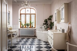 Bathroom features a bathtub, vanity, and radiator, with potted plants adding a touch of greenery.