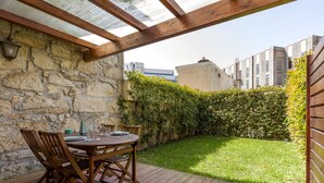 Un patio con un muro in pietra, mobili in legno e un tetto in vetro.