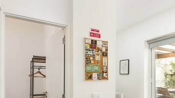 A modern interior with a wooden floor, a bulletin board, and a sliding glass door leading to an outdoor area.