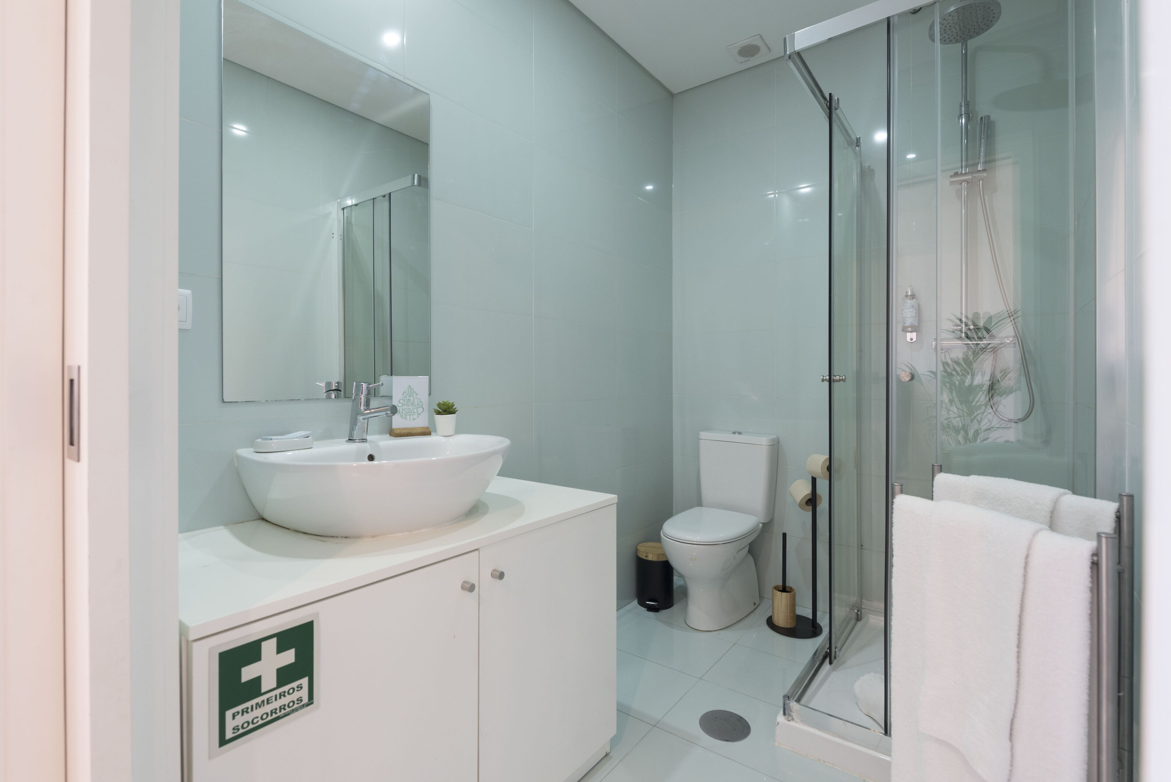 A modern bathroom with a large mirror, a white sink, a toilet, and a glass-enclosed shower area.