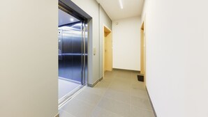 A hallway with a closed elevator and a door leading to another room. - Friendly Apartments - Kościelna (Poznan)