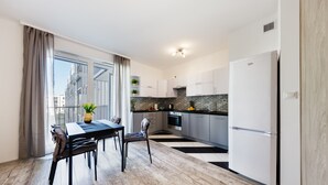 A modern kitchen with a dining area, featuring a black and white checkered floor, a dining table with chairs, and a refrigerator. - Friendly Apartments - Kościelna (Poznan)
