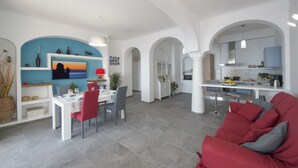 Una sala de estar moderna con un sofá rojo, un comedor con una mesa y sillas blancas y una cocina con barra.
